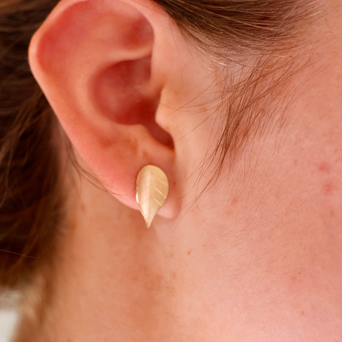 9ct gold earring on earlobe - matt finish and engraved leaf pattern